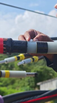 Close up video of worker hands in safety gloves applying semiconducting stress control mastic on a twisted aerial cable joint, industrial electrical power grid distribution network maintenance.