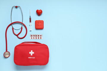 Obraz premium First aid kit with stethoscope, pills box, red heart and syringe on blue background
