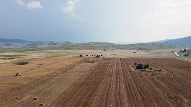 Landscape showing a rural farming valley surrounded by low hills from an aerial perspective. Drone view of a flat agricultural plain and karst field in the countryside.