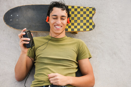 Young man listening music with cassette player - New trend people lifestyle using vintage analog device - UGC content - Focus on face