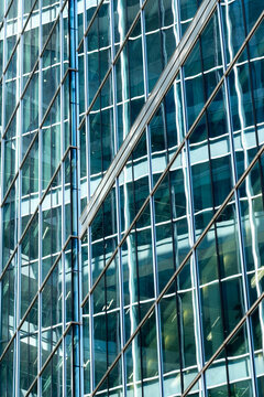 Glass office facade with diagonal supports and reflective windows creating an abstract architectural pattern of lines structure and urban geometry