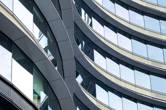 Abstract curved modern building facade with windows and balconies creating a flowing architectural pattern of layered lines and urban rhythm