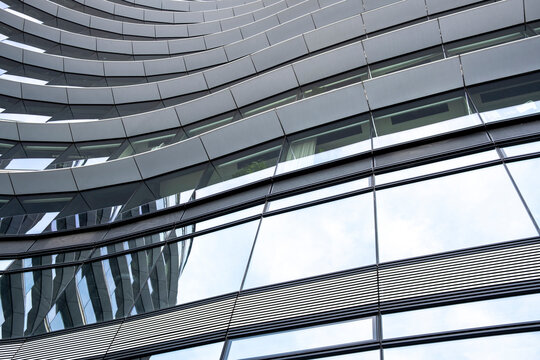 Abstract curved building facade with reflective windows and horizontal lines creating a modern architectural pattern in an urban detail