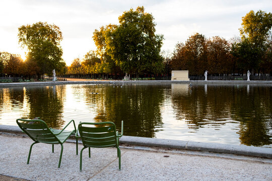 Chairs beside a pond in Tuileries Garden Paris France create a quiet autumn park scene with reflections across the water and chairs facing the pond