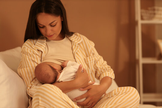 Mother breastfeeding her baby on bed at night