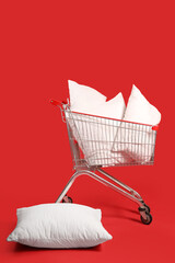 Shopping cart with soft pillows on red background © Pixel-Shot