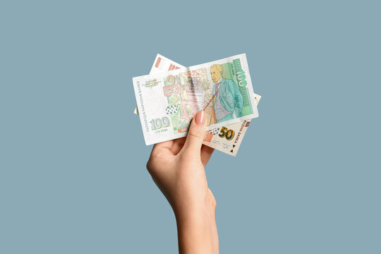 Female hand holding Bulgarian lev banknotes on blue background