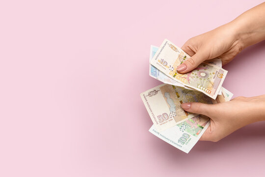 Female hands holding Bulgarian lev banknotes on pink background