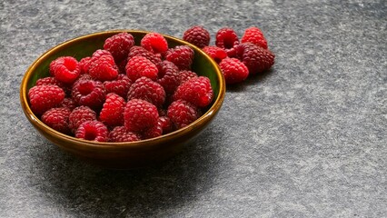 Fresh raspberries in ceramic bowl on grey stone background © Анатолий Еремин