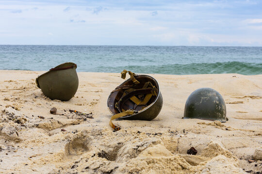 Three American infantry helmets from World War II on the beach.

