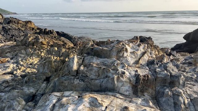 Panoramic panning view of unique rock formations and lush green hill on Vagator beach in Goa India