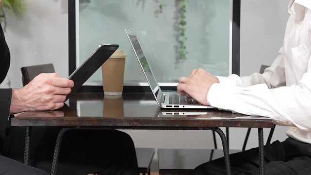 A businessman's hands are typing on a laptop and writing code at a coffee shop. The concept is to work from anywhere.