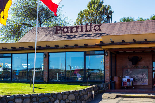 The rustic exterior of Parrilla Los Ganaderos in the Maule Region of Chile features brick walls, wood accents, large windows, and a decorative bull head above the entrance