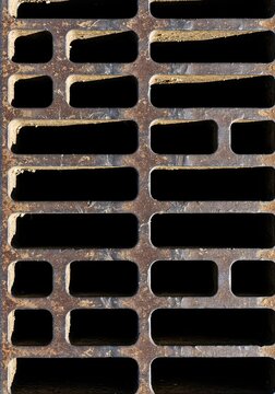 Close up shot of a heavy duty metallic drainage grate showing repetitive geometric patterns and industrial texture with signs of wear and age ,repetitive ,rough ,abstract