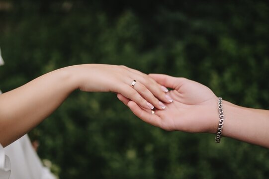 Wedding photo of the newlyweds, the groom and the bride touching each other with their hands and fingers.