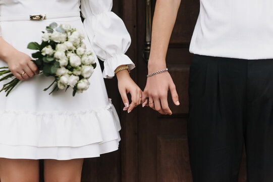 Close-up wedding photo of newlyweds holding hands.
