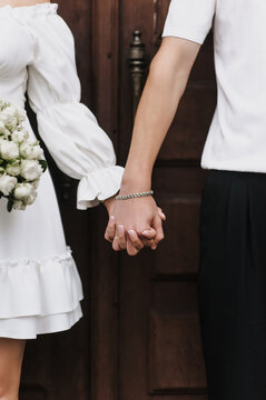 Close-up wedding photo of newlyweds holding hands.