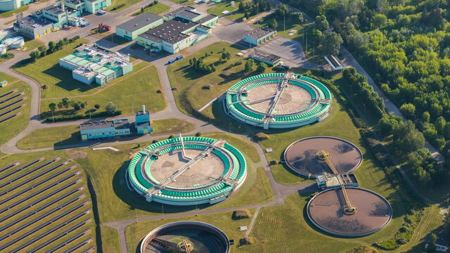 Aerial view of a wastewater treatment plant with large circular clarifiers, treatment tanks, and sludge facilities in Warsaw, Masovian Voivodeship, Poland.