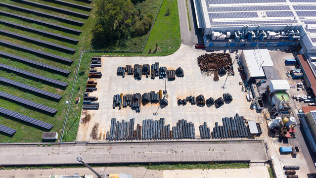 Aerial view of industrial hardware production facility with stacks of metal fasteners, screws, and bolts stored in an outdoor yard in Cornaredo, Lombardy, Italy.