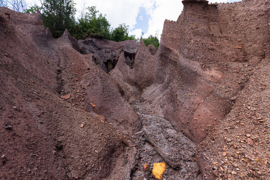 A narrow eroded gully winds through the steep red mineral hills of Le Roste di Montieri. These striking barren badlands reveal the raw industrial heritage and deep geological history of Tuscany.