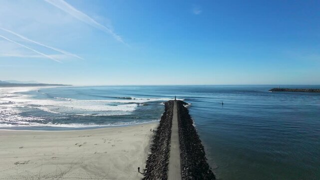 Aerial drone view following the path to a lighthouse in Viana do Castelo, Portugal, with powerful Atlantic waves breaking along the rocky coastline.