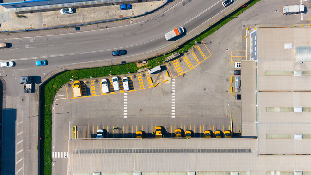 Aerial view of the Esselunga Spa logistics facility featuring a large parking area with marked bays, delivery trucks, and an adjacent road in Sesto Ulteriano, Lombardia, Italy.