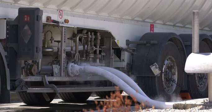 Daytime static eye level shot showing pressure vapor emissions as a tanker truck loads LPG liquid petroleum gas at Coastal Petroleum Dominicana terminal in San Pedro de Macoris, Dominican Republic.