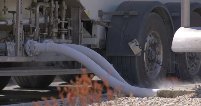 Daytime eye level shot with camera panning as a technician monitors LPG gas transfer hose connections at Coastal Petroleum Dominicana terminal in San Pedro de Macoris, Dominican Republic