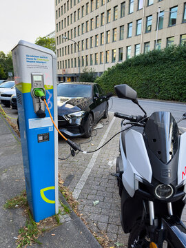Ein E-Roller und ein E-Auto werden an einer Ladestation geladen in Wuppertal, Deutschland