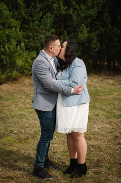 Loving expecting parents kissing each other tenderly outdoors in a forest during a twin gender reveal photo shoot.