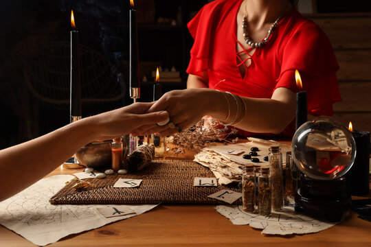 Fortune teller reading womans palm at table