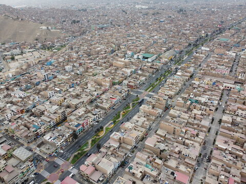 Aerial view of Avenida Peru cutting through the dense residential urban landscape of San Martin de Porres, Lima, Peru.