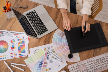 Obraz premium Female web designer with graphic tablet working at table in office, top view