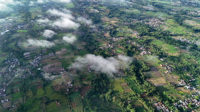 Aerial view of lush green rice fields and small villages scattered across the rural landscape of Sukabumi Regency, West Java, Indonesia.