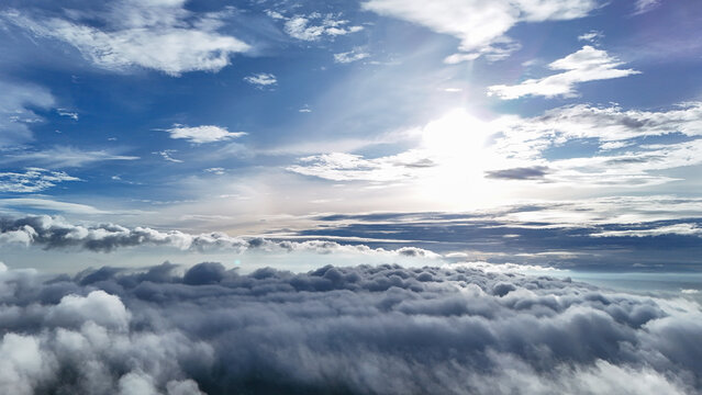 Aerial view of a vast expanse of fluffy white clouds under a bright blue sky with sunlight breaking through in Sukabumi Regency, West Java, Indonesia.