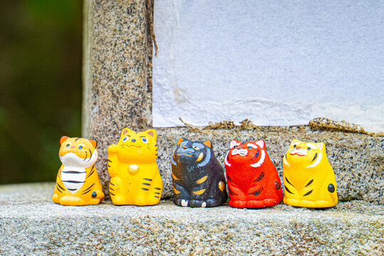 Five colorful tiger figurines lined up on a stone ledge