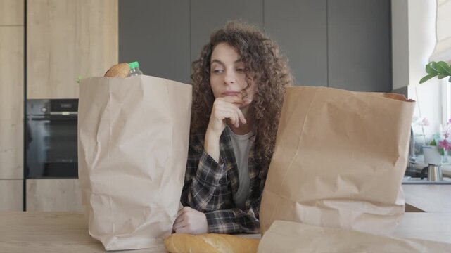 Woman Comparing Grocery Bags And Considering What To Prepare For A Meal