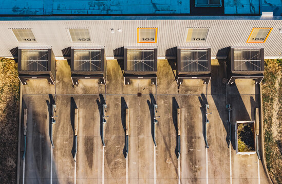 Aerial view of industrial service bays and technical infrastructure at a modern utility facility with numbered loading docks and concrete pavement in Valence, Auvergne-Rhone-Alpes, France.