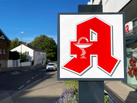 Schild mit Zunftzeichen oder Logo f&uuml;r Apotheke an einer Stra&szlig;e