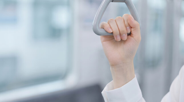 電車内で吊り革につかまる女性の手元と通勤風景