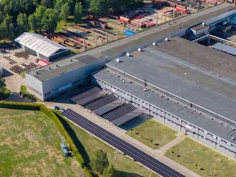 Aerial view of a modern factory building featuring rooftop and ground-mounted solar panels