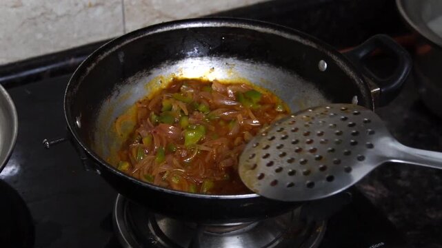 Close-up of saut&eacute;ing onion and capsicum in a wok.