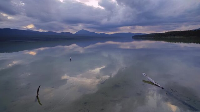 Calm mountain lake perfectly reflect cloudy sky timelapse and distant peaks at twilight