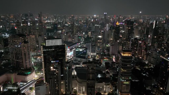 Dazzling high rise buildings illuminate the evening urban landscape of Bangkok as golden lights glow across the dense horizon of this bustling metropolitan center. Thailand 26 april 2026