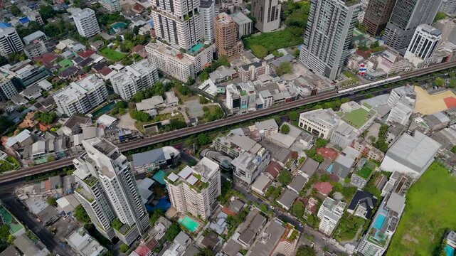 Skyscrapers and transit lines stretch across the vibrant city of Bangkok while sunlight illuminates the rooftops and streets during a clear afternoon