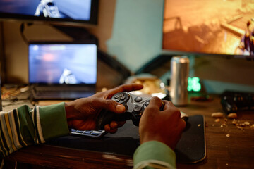 African American young adult man holding gamepad controller playing video game on computer screen. Image suitable for esports marketing, gaming addiction awareness, digital entertainment © Seventyfour