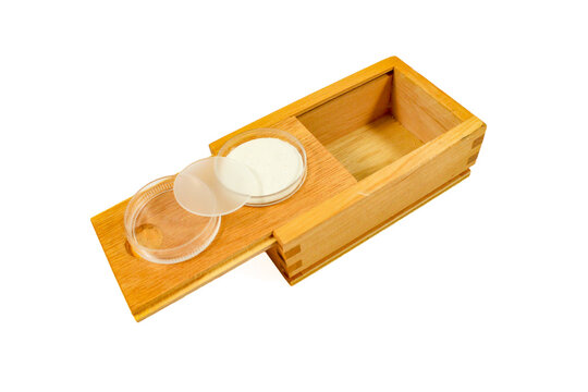 Set of round glass and optical discs with small glass dishes stored in a wooden case, isolated on a white background.