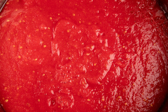 Tomato sauce background closeup with red fresh puree juice texture, juicy organic marinara paste macro pattern, top view flat lay for ketchup and pizza food packaging design.
