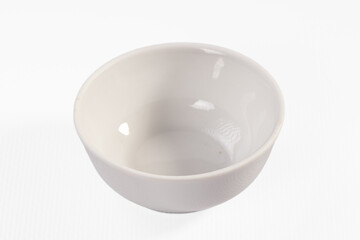 Empty white ceramic bowl on plain white background with soft shadows and glossy interior surface