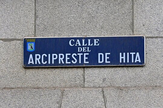 A blue street sign reading "Calle del Arcipreste de Hita" mounted on a facade in Madrid, Spain. The sign designates a street named after the medieval Spanish poet Juan Ruiz,August 28, 2026